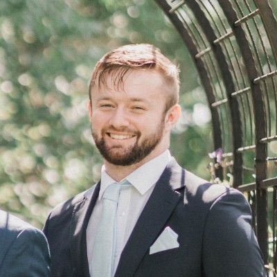 Man in a suit smiling outdoors.